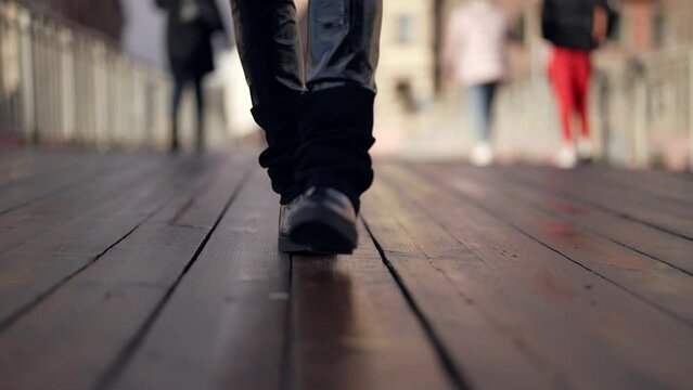 passer on bridge in city in autumn or winter day, closeup of feet, black female boots