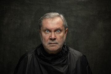 Fototapeta premium Portrait of angry senior man looking at camera isolated on dark vintage background. Concept of emotions, fashion, beauty, self-reinvention