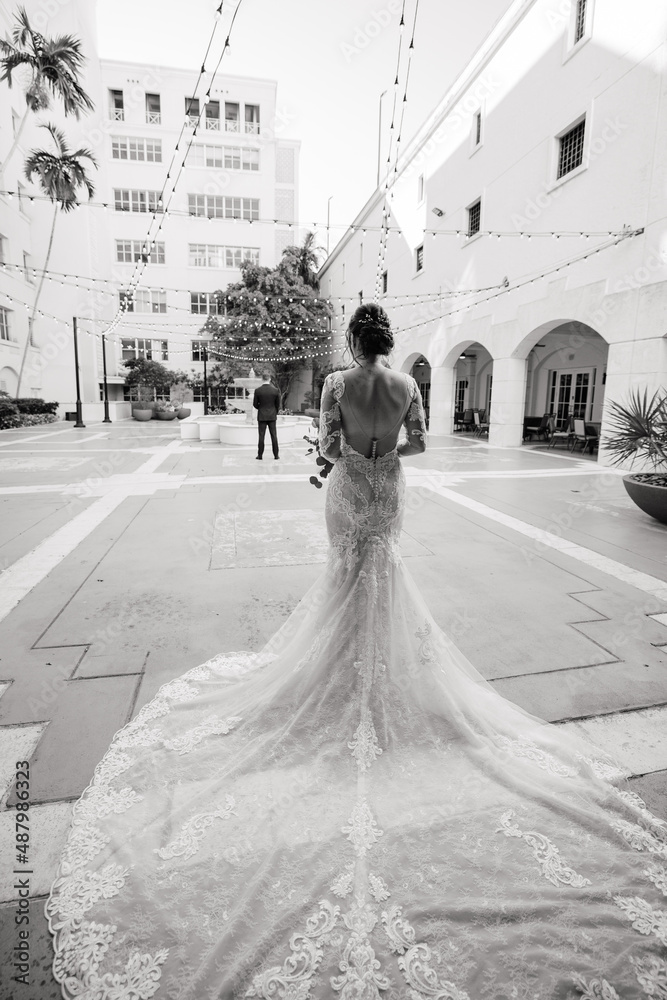 Wall mural The First meet of the bride in a white gown and groom in a black suit outdoors Groom waits for his beloved Outdoors Cropped photo Black & White photo Back view