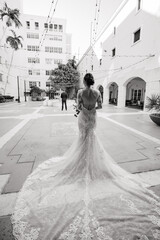 Obraz premium The First meet of the bride in a white gown and groom in a black suit outdoors Groom waits for his beloved Outdoors Cropped photo Black & White photo Back view