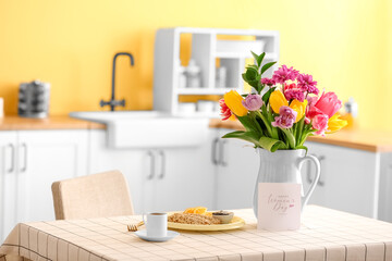 Beautiful flowers, breakfast and greeting card with text HAPPY WOMEN'S DAY on dining table