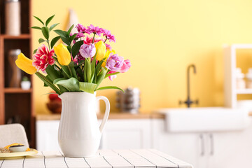 Jug with tulips in dining table in kitchen