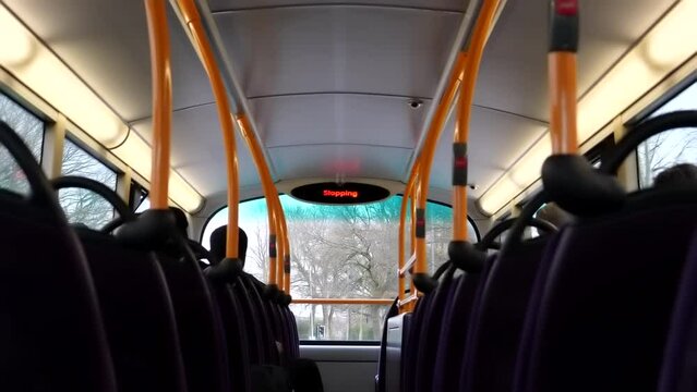 Blurred dark inside view of upper deck of double-decker bus and street travelling in town in England, selective focus on street.