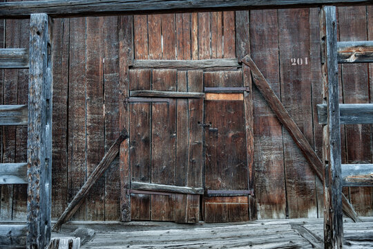 Parois d'une grange en bois ancien, porte de vieux mélèze foncé par le soleil