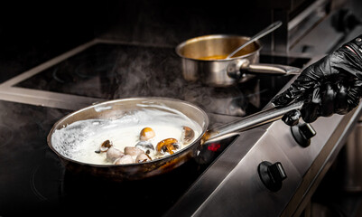 chef hand cooking sauce with mushroom sliced in pan at a restaurant kitchen