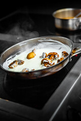 chef hand cooking sauce with mushroom sliced in pan at a restaurant kitchen