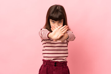 Little girl isolated on pink background making stop gesture with her hand to stop an act