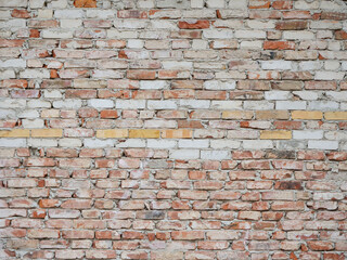 Old brick wall background texture with damaged stones. Dirty and dusty surface of a rough building exterior. Pattern of weathered fine masonry structure with different bricks.
