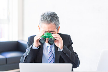 双眼鏡でパソコンを検証する男性