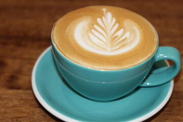 Turquoise cup of fresh cappuccino with beautiful latte art on old wooden background. Top View, coffee break