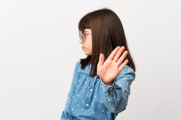 Little girl with sunglasses isolated on white background making stop gesture and disappointed