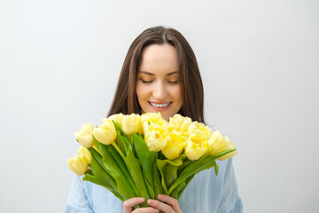 caucasian smiling brunette woman with yellow tulips with closed eyes