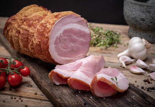 Smoked rolled bacon, pancetta, pork meat roulade, on wooden boards. Composition with Polish cold cuts, meat products.