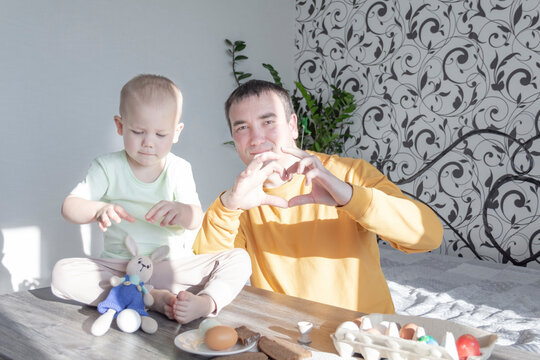 A dad celebrates Easter with his young son. They beat eggs, eat eggs and have breakfast. Dad teaches the child.