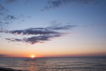 Beautiful sunset over sea with reflection in water, majestic clouds in the sky