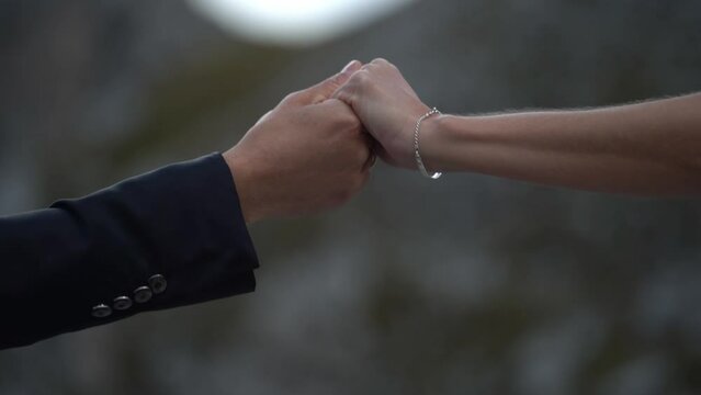 Male and female hand reaching each other holding gently and slowly leaving again - suit and bracelet