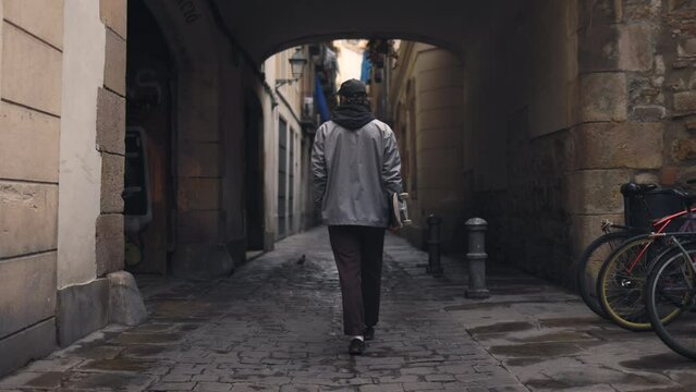 SKATEBOARDING - Skater walking down an alleyway in Barcelona, Spain, slow motion