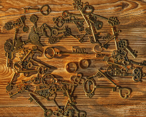 Fototapeta na wymiar Keys with LOVE inscription in piles of different keys and wedding rings
