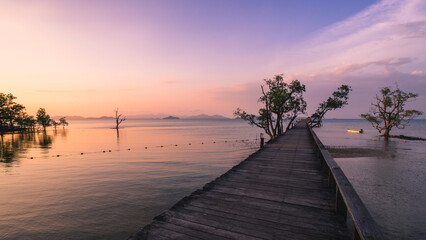 Naklejka na ściany i meble Scenic view of sea with infinity long wooden bridge boardwalk over peaceful bay of water in sunset orange sky. Koh Mak Island, Trat Province, Thailand.