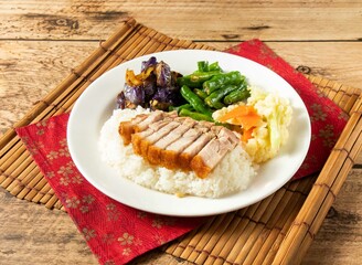 Crispy Roasted Pork Rice with green chili in white plate on mat isolated on wooden background top view chinese rice