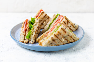 sandwich with ham cheese tomatoes lettuce onions on plate. Classic club sandwich with whole grain bread