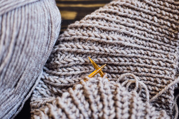 Knitted sweater with a knitting needles. Close up photo on grey background with copy space. Knitting class concept. home hobbies