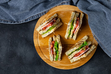 sandwich with ham cheese tomatoes lettuce onions on cutting board. Classic club sandwich with whole grain bread