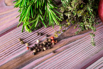 Thyme, pepper, rosemary on a purple wooden background. Various spices.