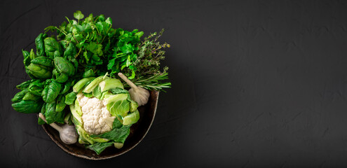 Whole cauliflower and various vegetables. Healthy, vegetarian food. Dark background. Place for text. Top view.