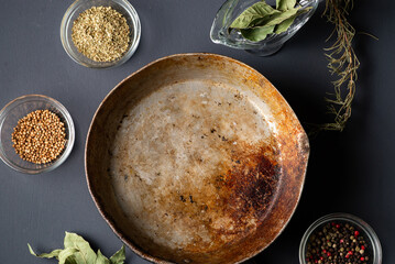 Empty rustic frying pan and various spices. Dark background. Cooking concept.