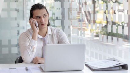 Finance workers are reviewing the company's financial data on a laptop and using smartphones to...