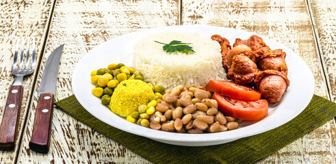 rice with brazil beans, served with salad, fried sausage and farofa. Served on a rustic table