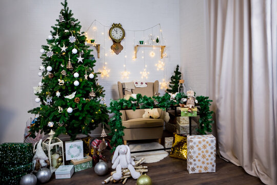 Christmas and New Year photo studio, green tree, soft chair, garlands stars, clock on a white wall (9). Idea for holiday like Christmas and New year, for covers books, magazines, articles.
