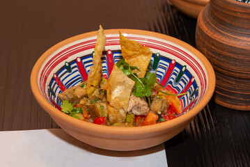 Caucasian kitchen. Warm salad in a clay bowl.