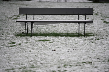 Parkbank in einem Park zur winterlichen Jahreszeit und mit leichtem Schnee bedeckt