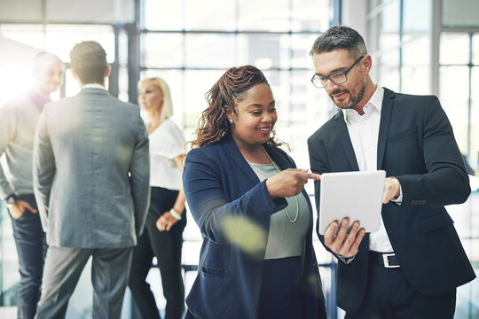 He trusts her business instincts. Shot of two coworkers talking together over a digital tablet in an office. - Powered by Adobe