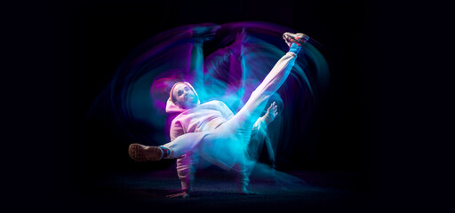 One energy young flexible sportive man dancing hip-hop or breakdance in white outfit on dark...
