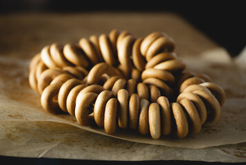 bunch of bagels lies on parchment paper, wooden background