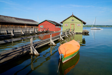 Obraz premium a long wooden pier leading to the colorful boat houses on lake Ammersee in the German fishing village Schondorf (Germany) 