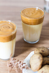Dalgona coffee with milk, dried eucalyptus vase and cookies on wooden table.