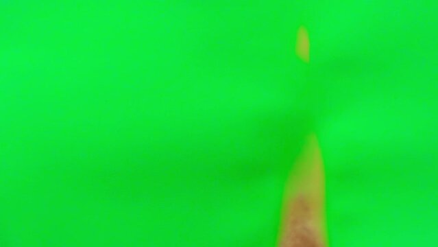 Chroma key burns, revealing burnt edges, smoke and turns into ashes. Burning green screen over blue background