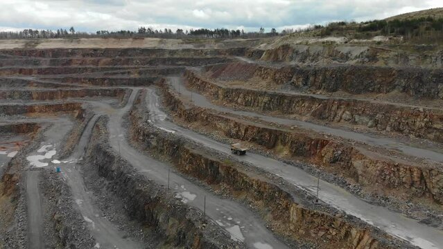 Aerial yellow belaz earthmoving truck in riding in granite open pit quarry.