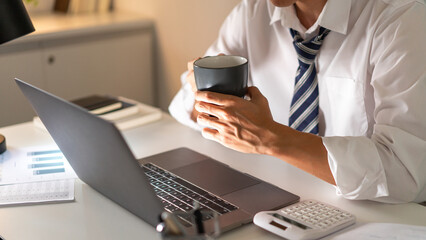 Overwork Concept An office man who works late drinking a cup of coffee while concentrating on his...