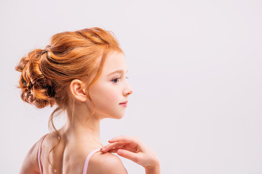 Portrait of a little red-haired girl ballerina on a white