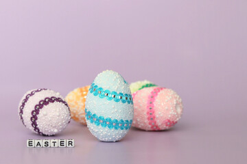 Decorative multicolored Easter eggs, easter inscription on a purple background, Easter holiday concept