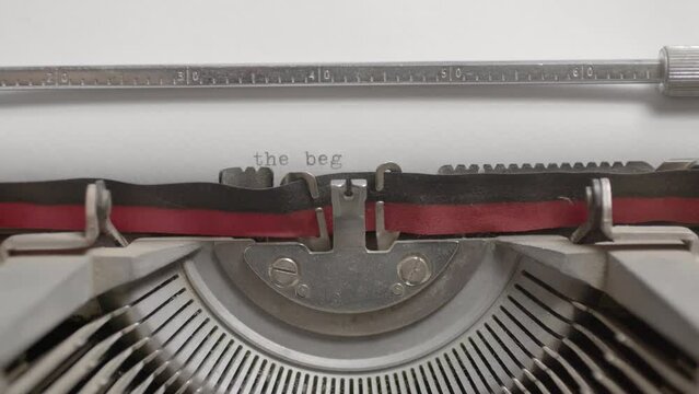 Closeup of a typewriter machine writing The Beginning