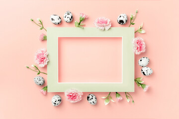 Happy Easter concept. Frame of Easter eggs and spring flowers on pink paper background. Flat lay, copy space.