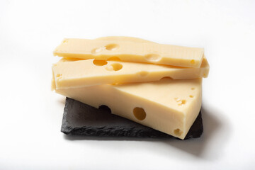 Maasdam cheese on a white background for insulation. Maazdam cheese on a stone board
