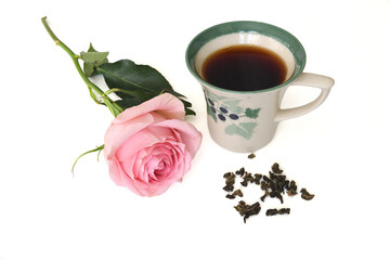 Cup of strong black tea and pink rose with water drops