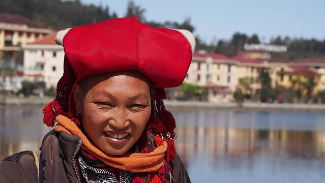 Red Dao ethnic minority woman wearing traditional headgear and smiling in Sapa, Lao Cai Province, Vietnam.	